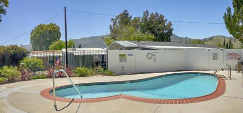 A swimming pool in front of a house with a fence.